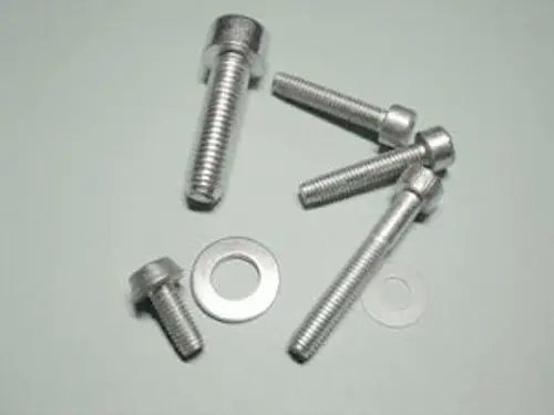 Schrauben und Unterlegscheiben aus Metall, möglicherweise von der Marke Remeha, auf einer hellen Oberfläche angeordnet.